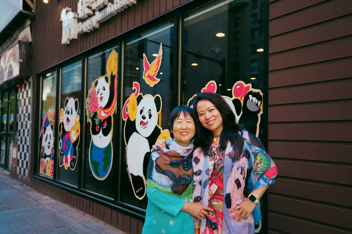 Xiang Li and Fei Wu standing in front of their panda mural on the Happy Lamb Hot Pot storefront in Boston’s Chinatown