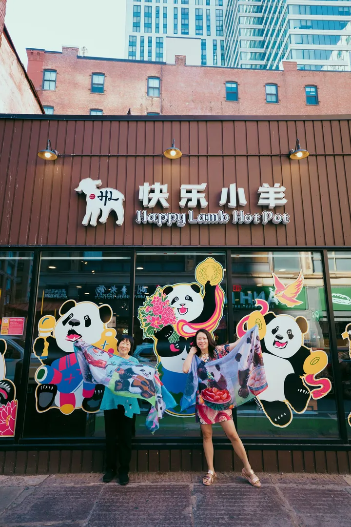 A visitor in a printed silk scarf in front of the panda mural on the Happy Lamb Hot Pot storefront in Boston’s Chinatown