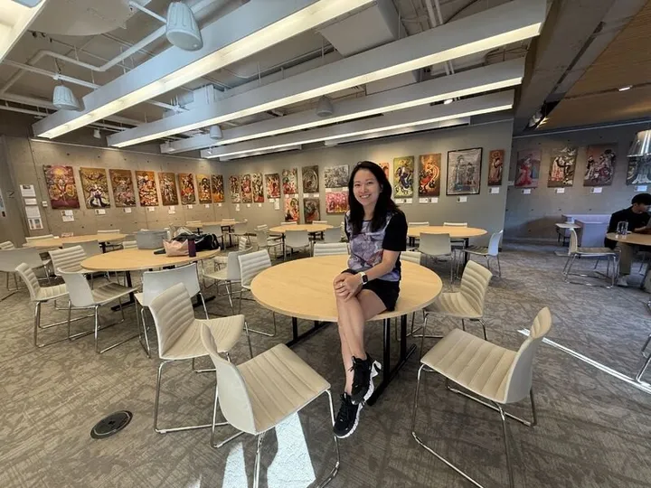 Fei Wu seated in a Gutman Library common room whose walls are lined with Xiang Li’s empress paintings