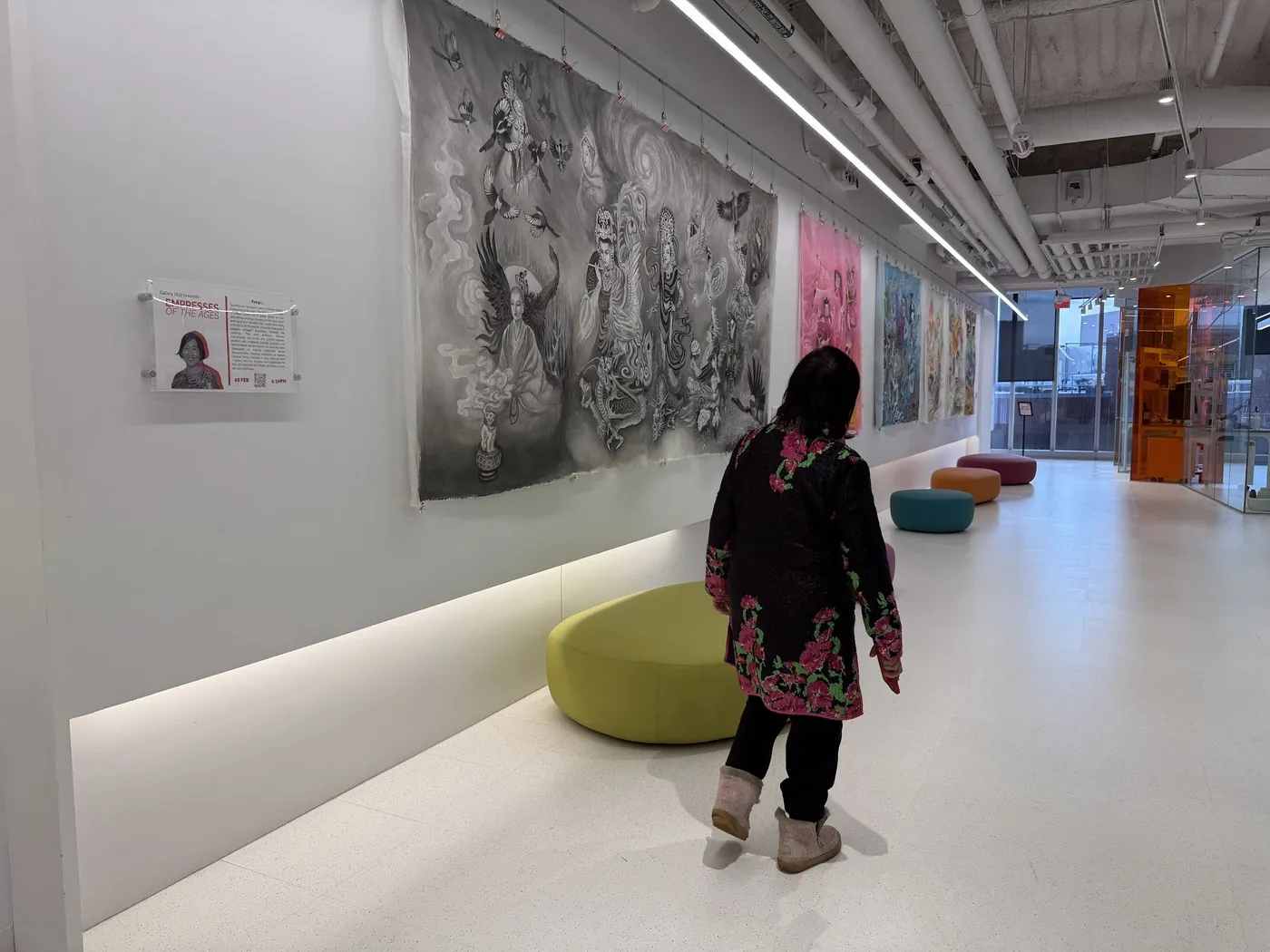 Silk paintings in ink and in color hung along a LabCentral corridor with Xiang Li standing beside them