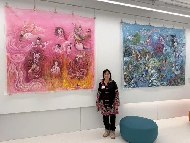 A pink and a blue silk painting hung side by side above low seating, Xiang Li standing between them