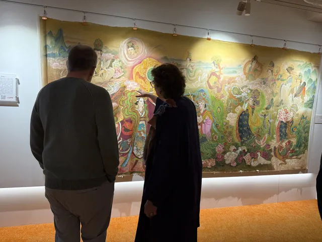 Two visitors looking closely at a wide silk scroll at LabCentral