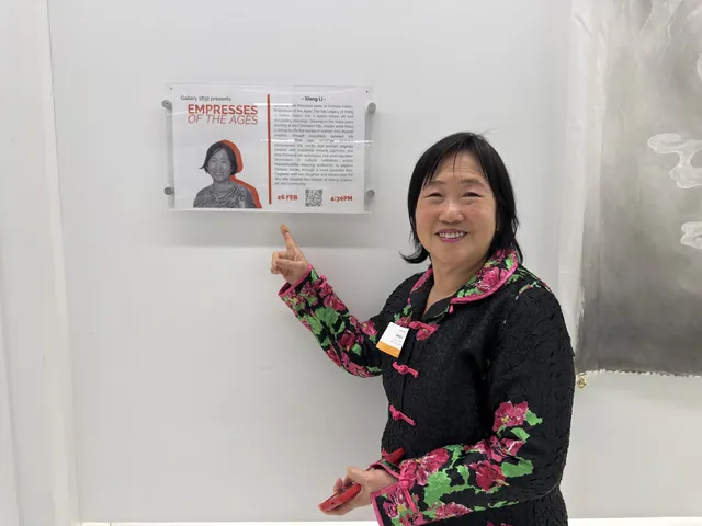 Xiang Li pointing to the Gallery 1832 wall label for Empresses of the Ages