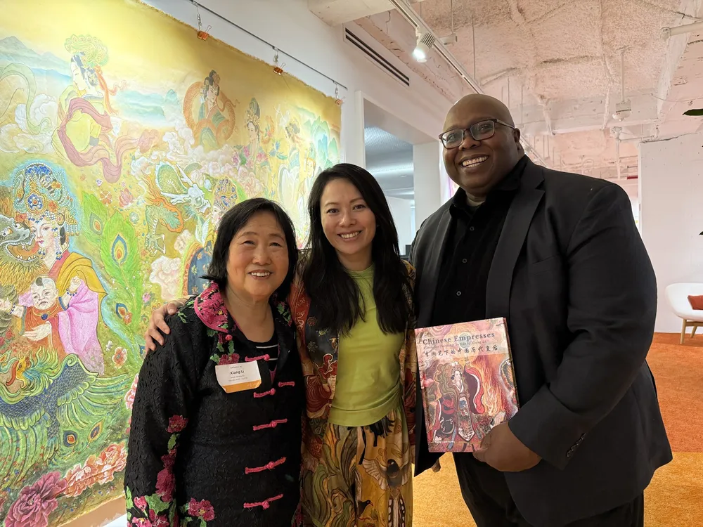 Xiang Li and Fei Wu with a guest holding the Chinese Empresses book, in front of a silk scroll at LabCentral