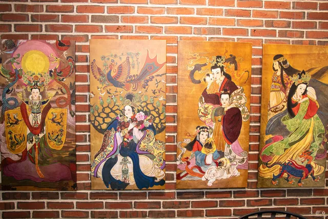 Four large empress portraits on canvas hanging on a brick gallery wall