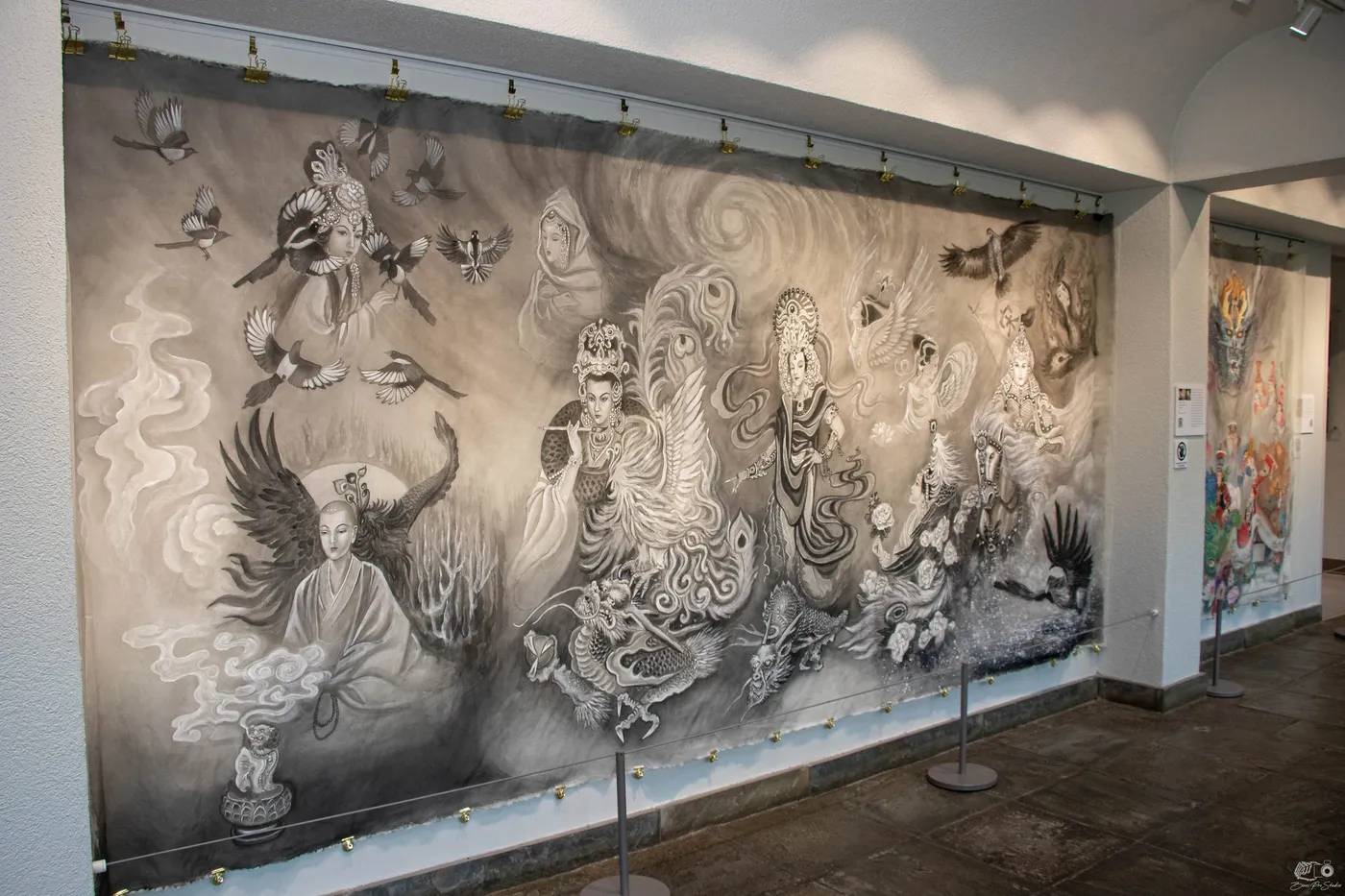 A long silk mural painted in ink and grey hanging in a Tower Hill gallery