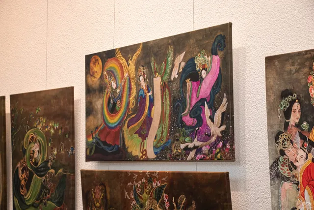 Landscape and portrait canvases of different sizes hung together on a white gallery wall