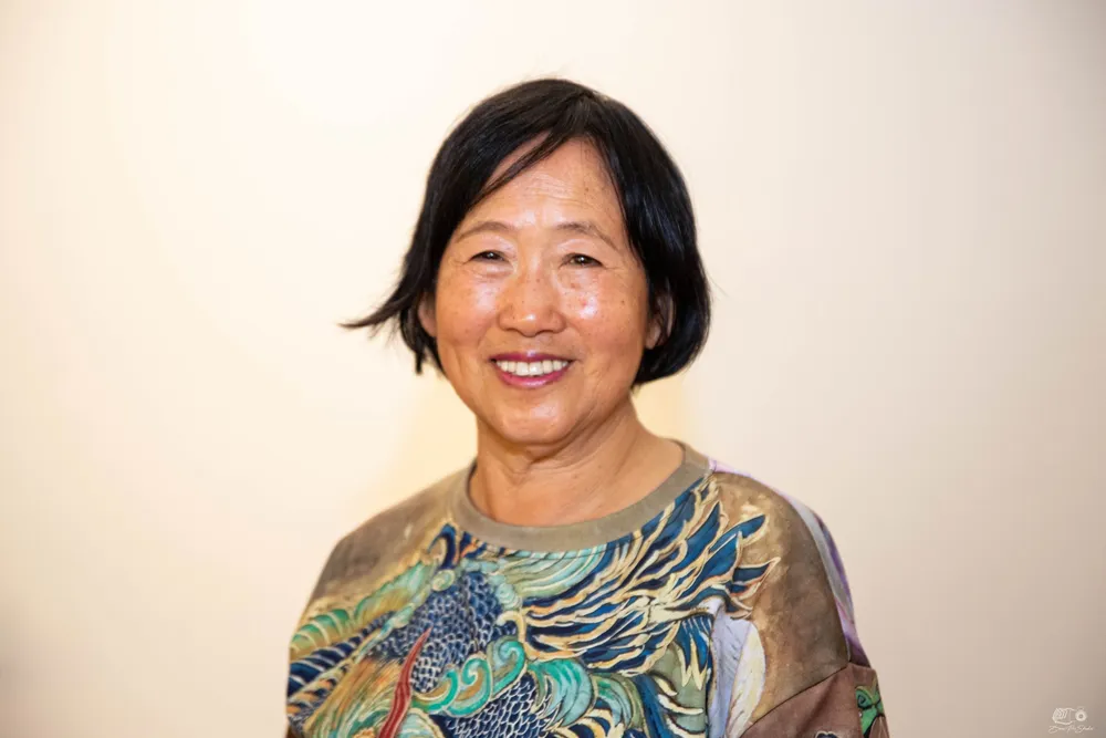 Xiang Li, photographed in 2024, wearing a silk top printed with one of her own phoenix paintings