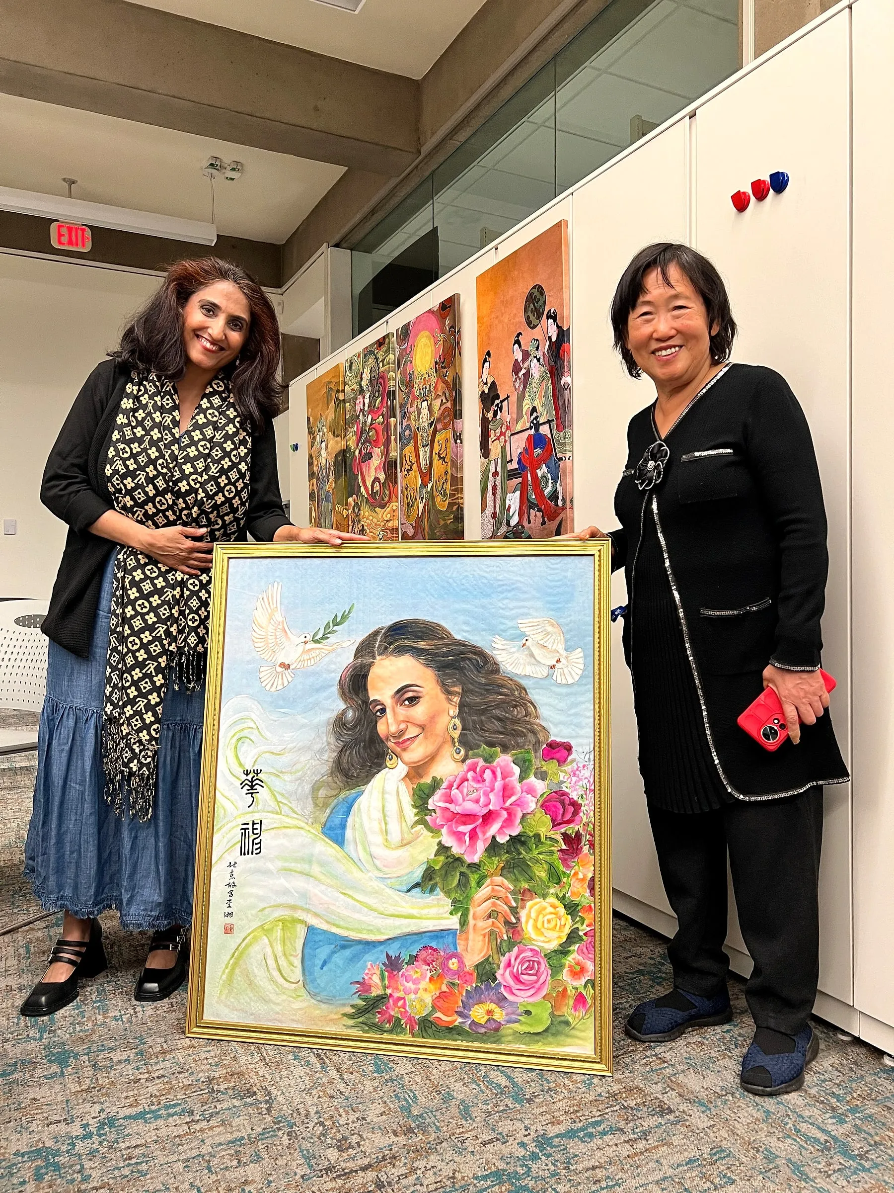 Tripti Gore Chandorkar and Xiang Li standing either side of the framed portrait