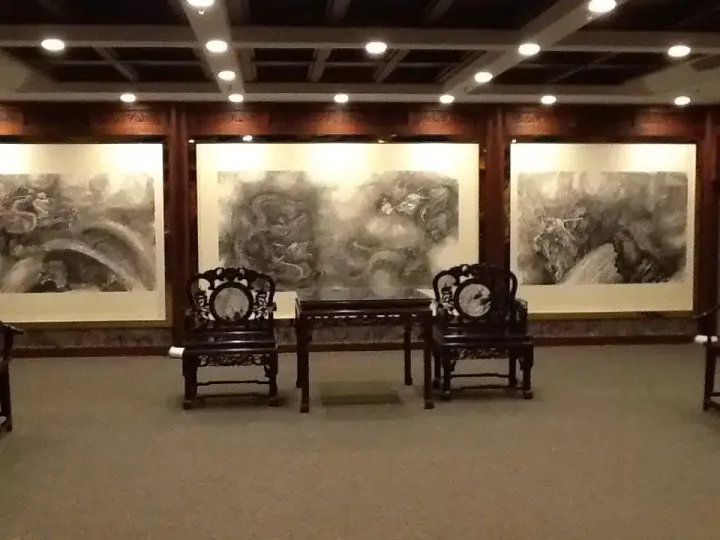 The guest area of the Shenzhen office: three large ink dragon paintings by Xiang Li above a pair of carved wooden chairs
